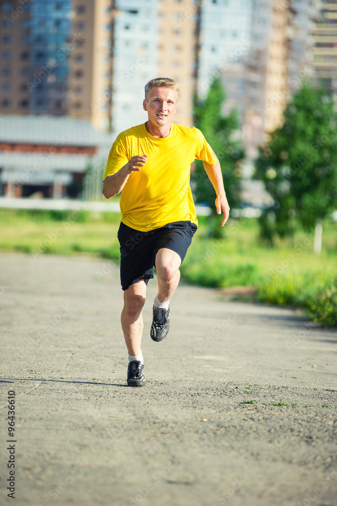 Sporty man jogging in city street park. Outdoor fitness. Sporty man jogging in city street park. Outdoor fitness.