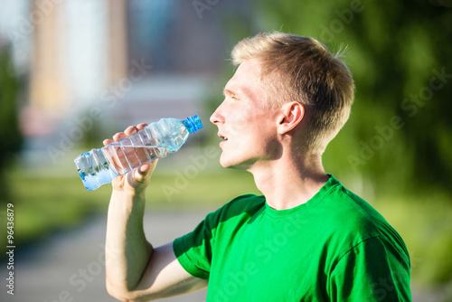 Tired man drinking water from a plastic bottle after fitness