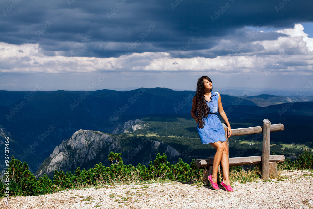 woman relax on peak of mountain with rainy sky