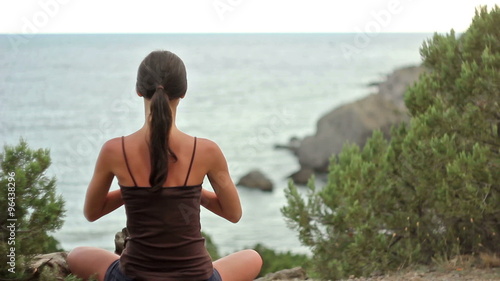 Fitness brunette girl doing yoga by the seaside with relaxing mountain view