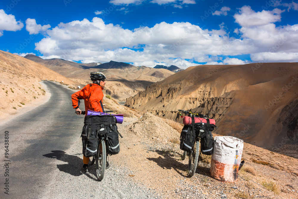 Cyclist standing on mountains road. Himalayas, Jammu and Kashmir State, North India Cyclist standing on mountains road. Himalayas, Jammu and Kashmir State, North India