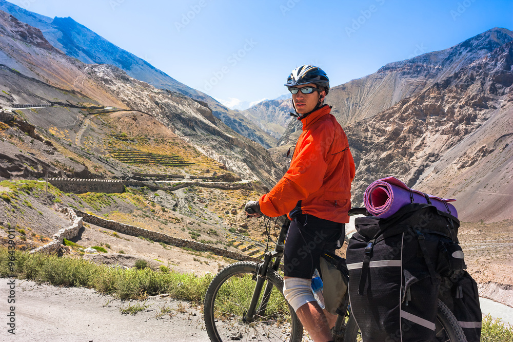 Fototapeta premium Young bicyclist standing on mountain road, Jammu and Kashmir State, North India