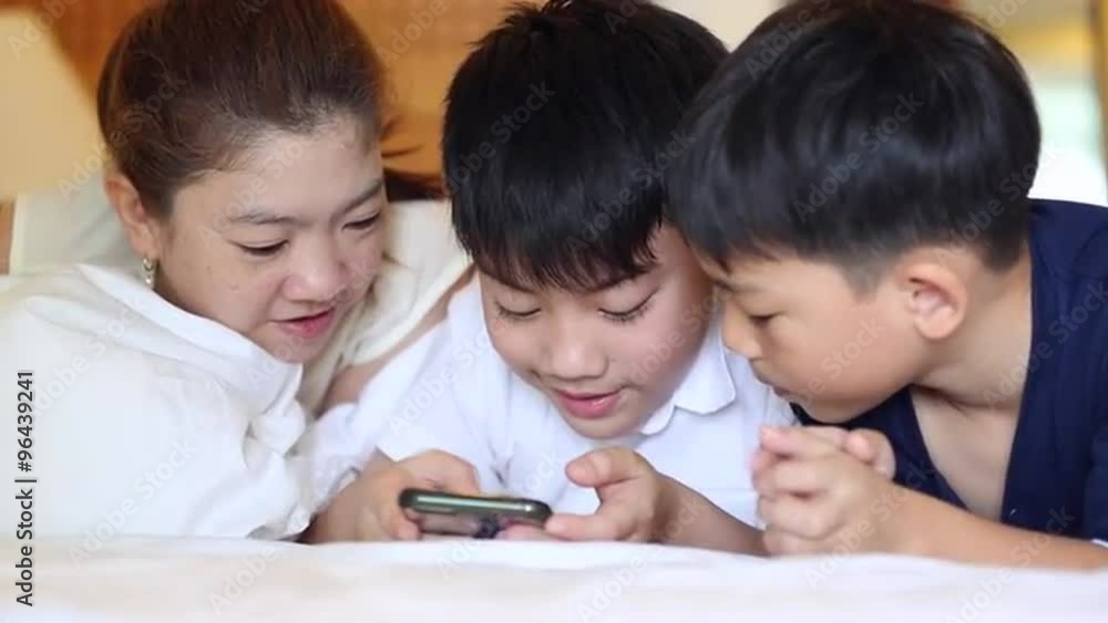 Happy Asian family are playing on tablet, smiling, laying on bed. Happy Asian family are playing on tablet, smiling, laying on bed.