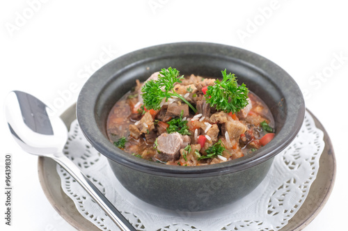Beef stew with celery in a stone bowl isolated on white