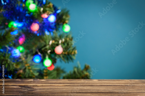 Wooden table with Christmas tree in the background. Focus on the table..