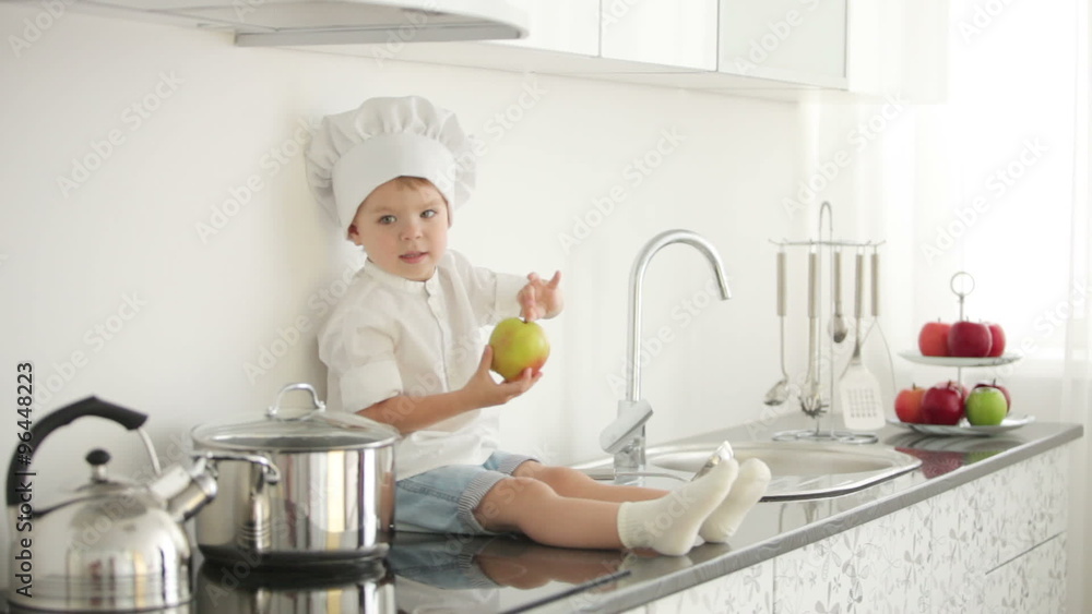 Little boy sitting on table and holding an apple Little boy sitting on table and holding an apple