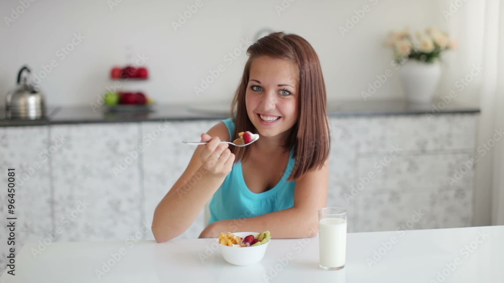 Beautiful girl sitting at table and eating salad Beautiful girl sitting at table and eating salad