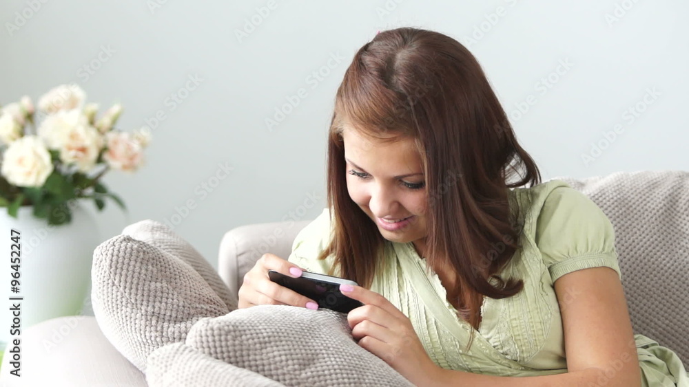 Cute girl relaxing on sofa and using cellphone Cute girl relaxing on sofa and using cellphone