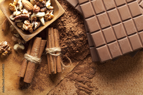 Chocolate bars, mixed nuts, cocoa and cinnamon sticks photo