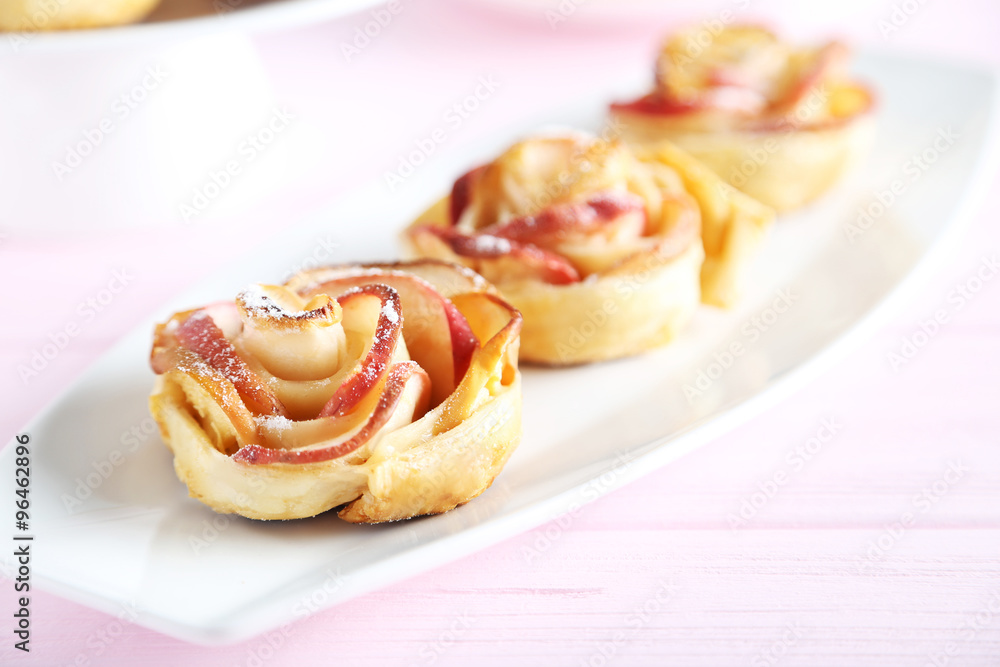Fresh puff pastry with apple shaped roses on pink wooden table