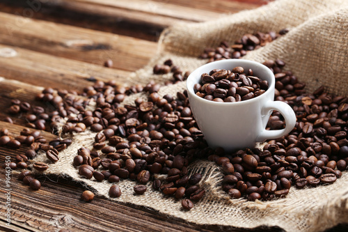 Coffee beans in cup on a brown wooden background