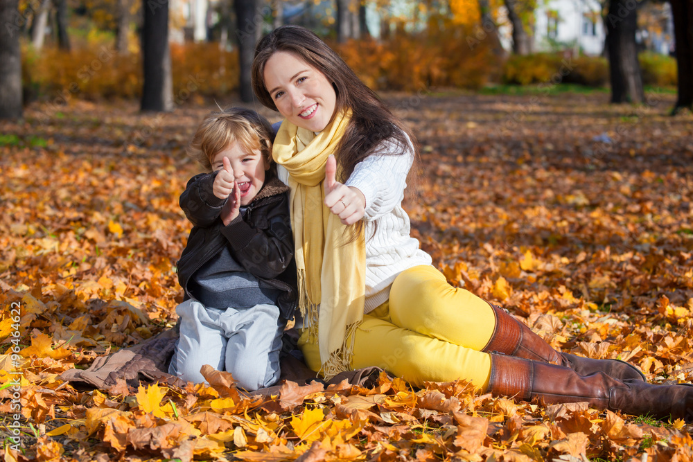Fototapeta premium Mother and son showing thumbs up in park.