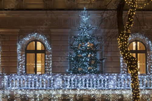 Building facade with light decoration at night with Christmas tr
