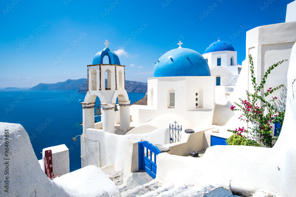 Fototapeta premium Malowniczy widok na białe domy i niebieskie kopuły na Santorini