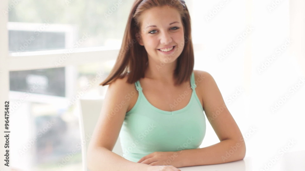 Attractive young woman sitting at table using touch pad and smiling at camera Attractive young woman sitting at table using touch pad and smiling at camera