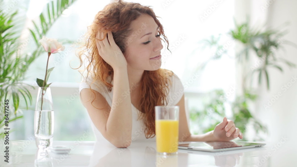 Attractive young woman sitting at table and using touchpad Attractive young woman sitting at table and using touchpad
