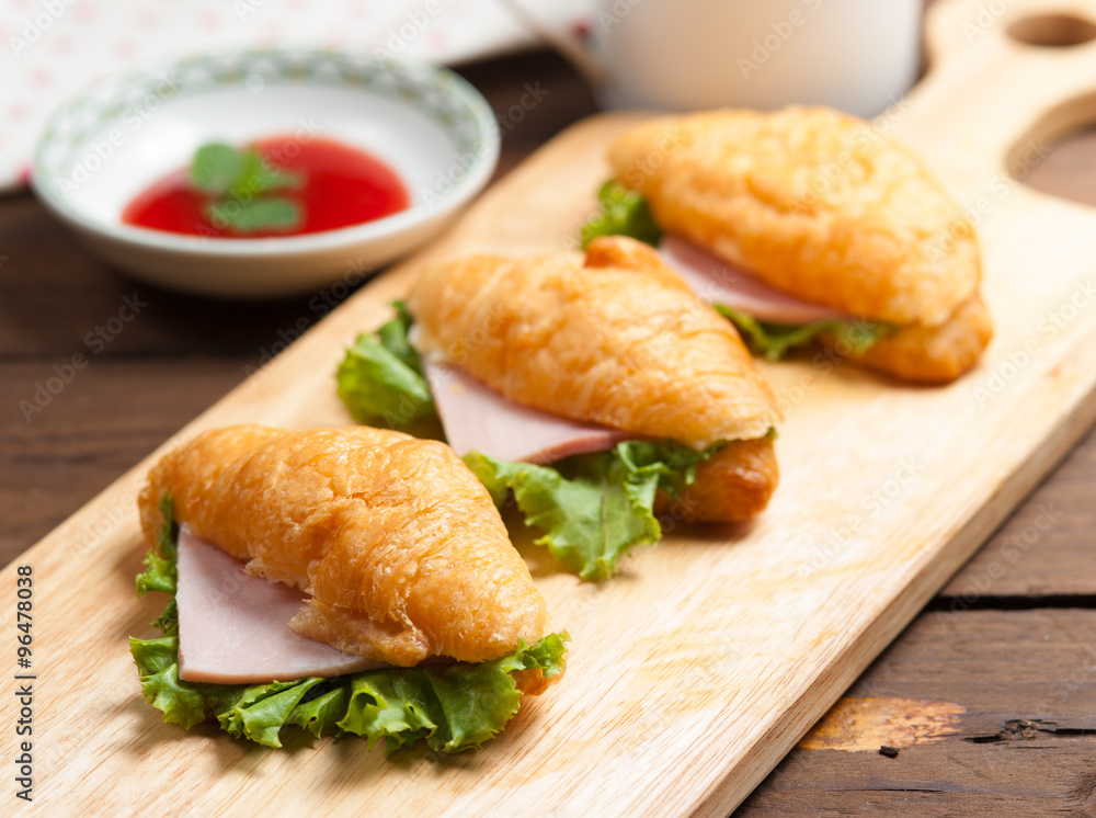 Fresh croissant ham and salad leaf with sauce on dark wooden bac Fresh croissant ham and salad leaf with sauce on dark wooden bac