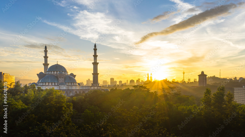 Naklejka premium Wschód słońca w Federal Mosque Kuala Lumpur, z panoramą miasta sylwetka
