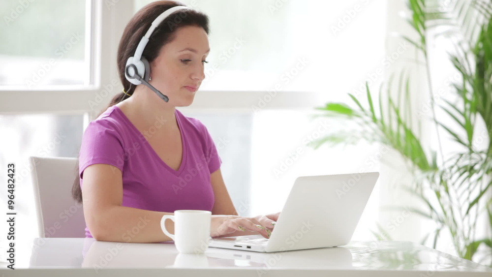 Beautiful call centre operator working on laptop and smiling
