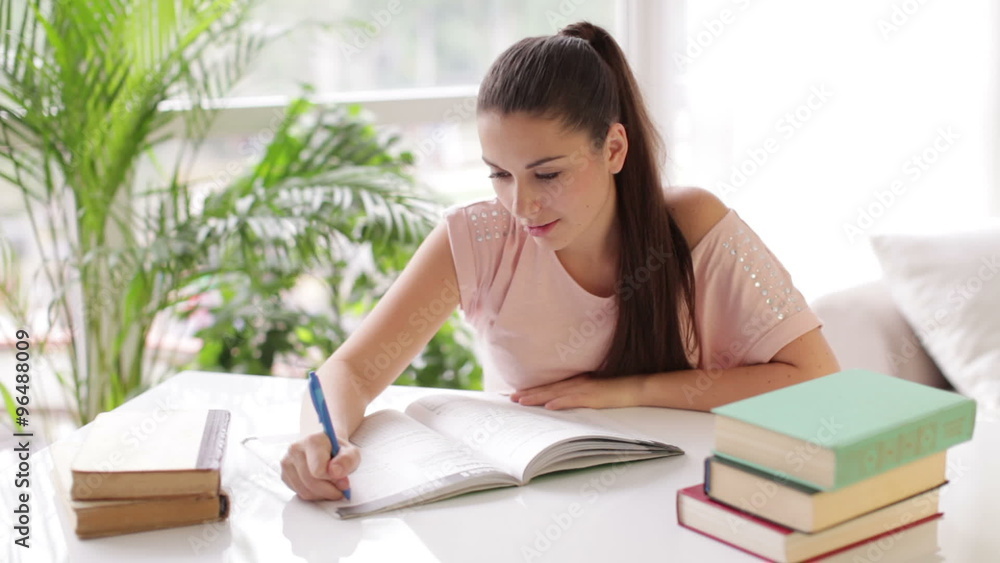 Cheerful student girl studying at table with books and smiling Cheerful student girl studying at table with books and smiling