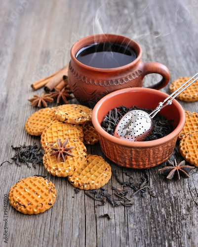 A cup of hot tea with cookies on a rustic wooden background