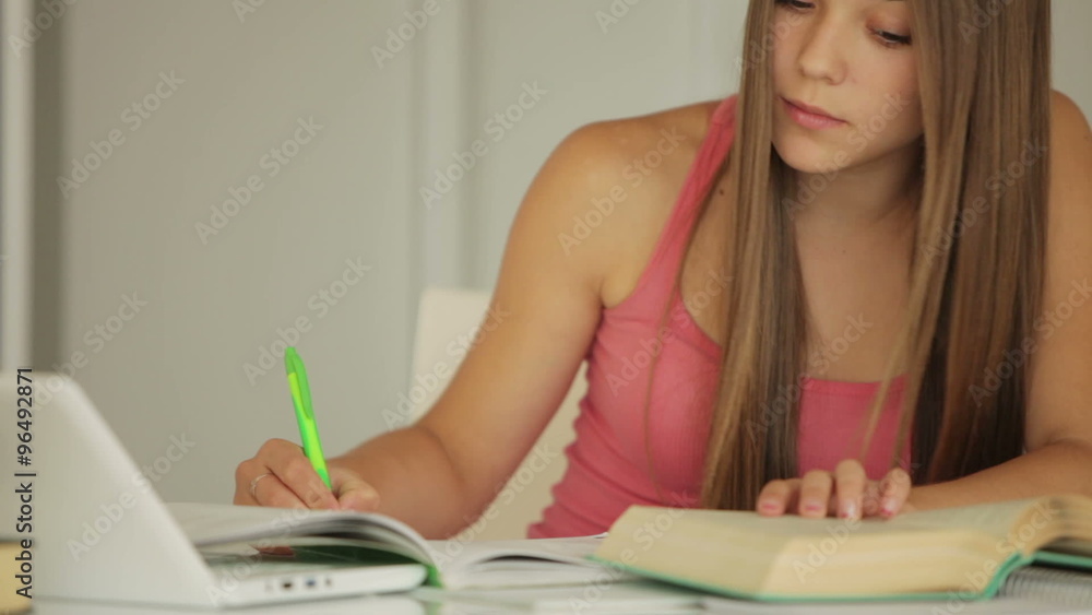 Charming girl sitting at table and writing in notebook Charming girl sitting at table and writing in notebook