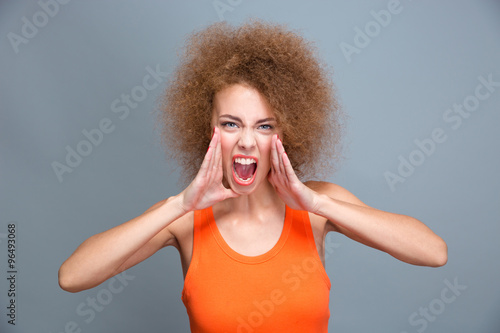 Portrait of angry furious young curly screaming woman photo