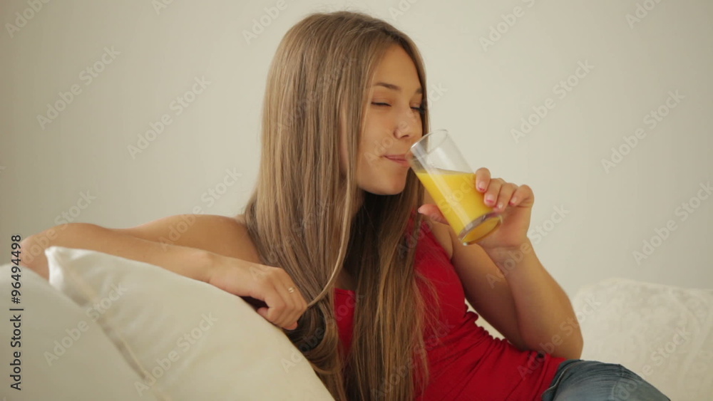 Cute girl relaxing on sofa drinking juice and smiling Cute girl relaxing on sofa drinking juice and smiling