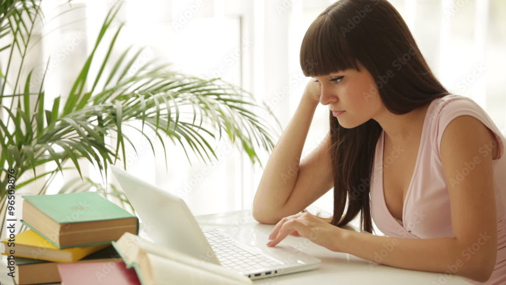 Student girl sitting at table and using laptop Student girl sitting at table and using laptop