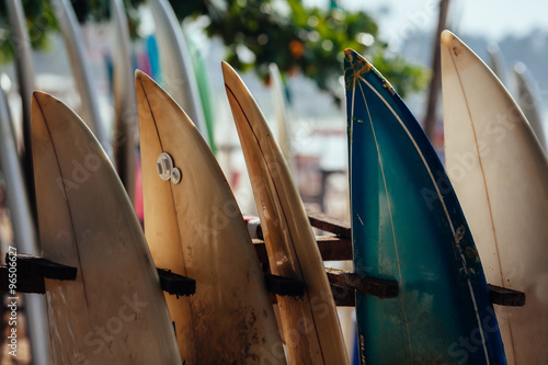 Set of different color surf boards in a stack by ocean. WELIGAMA. Surf boards on sandy Weligama beach in Sri Lanka. On Weligama beach surf is available all year around for beginner and advanced. photo