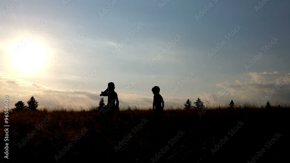 Little boys running free on green meadow at sunset Little boys running free on green meadow at sunset