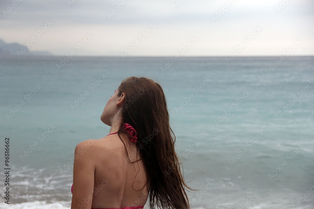 Girl stands with his back to the sea