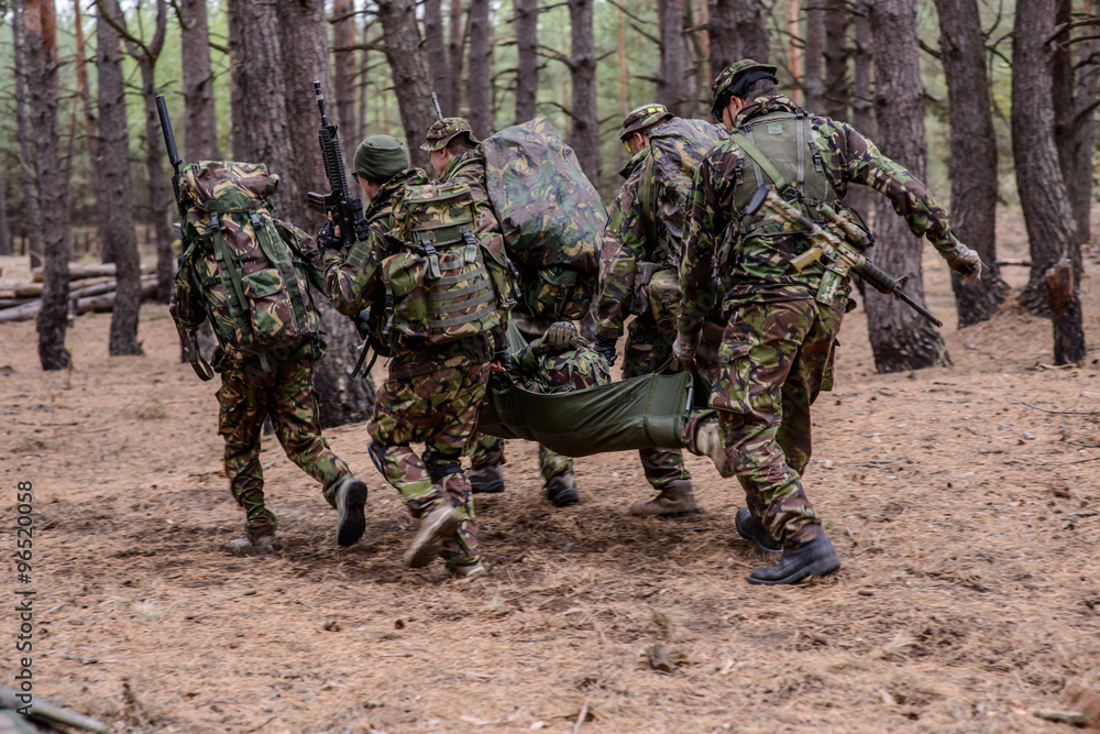 Soldiers run away from the battlefield with stretcher and wounde Soldiers run away from the battlefield with stretcher and wounde
