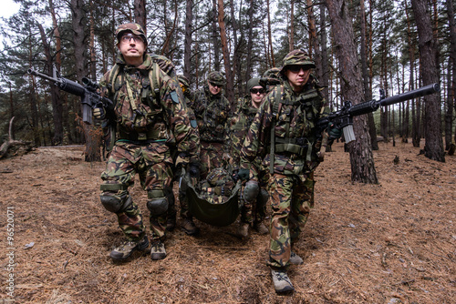 Squad of soldiers evacuating wounded trooper from battlefield
