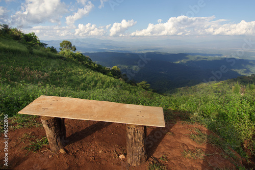 View of a lonely chair, grass, mountain, and cloudy blue sky in Chiangmai city Thailand