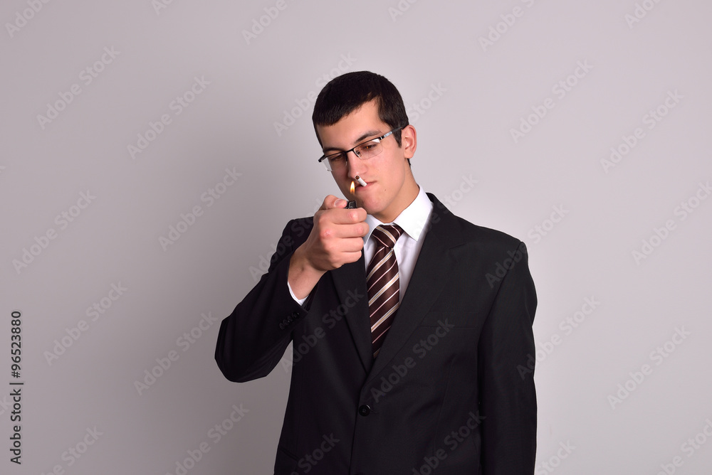 young man dressed in tuxedo lighting cigarette in studio young man dressed in tuxedo lighting cigarette in studio