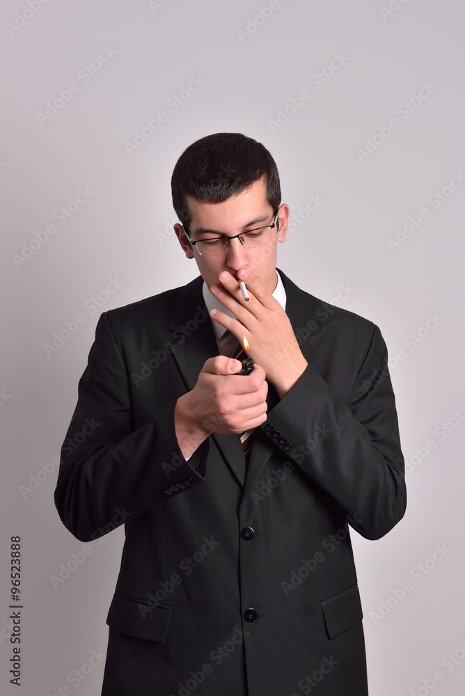 young man dressed in tuxedo lighting cigarette in studio young man dressed in tuxedo lighting cigarette in studio