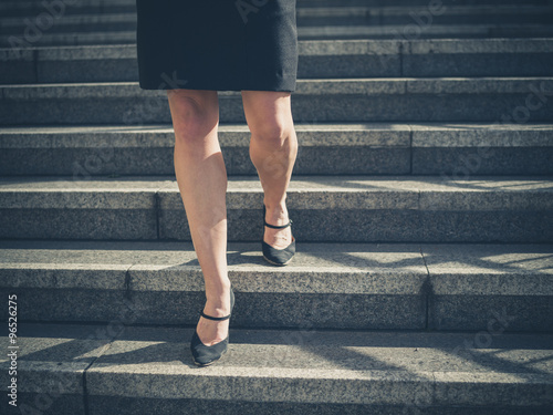 Legs of young businesswoman in city on stairs