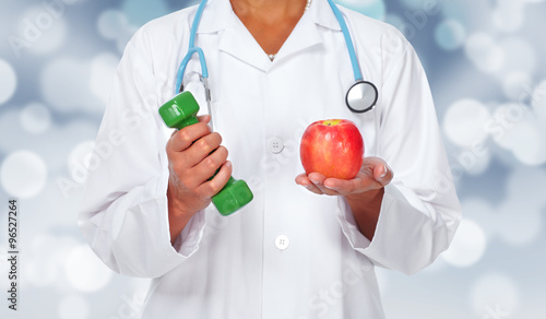 Doctor woman hands with dumbbell and apple.