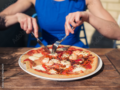 Young woman cutting pizza