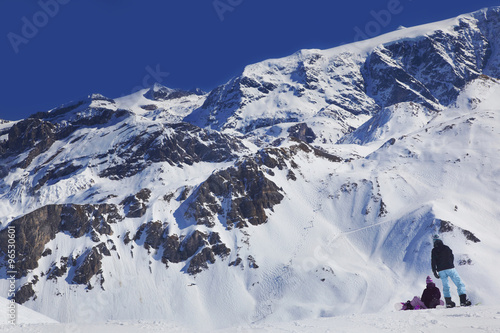 Snowboarders pause on a ridge above an off-piste slope in The Three Valleys ski resort, France.