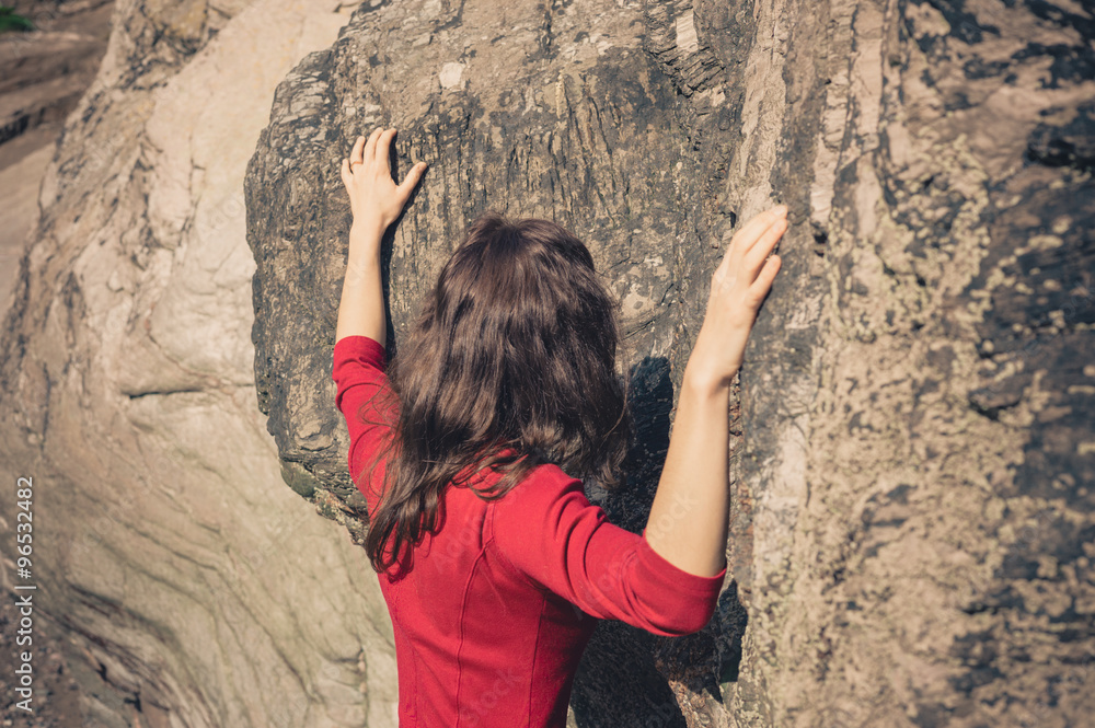 Woman in red dress touching rock wall