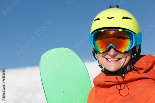 portrait of a snowboarder smiling on the top of the mountains photo