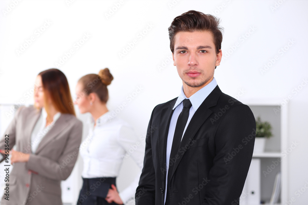 Cheerful business man in office with colleagues in the background, sturt up team Cheerful business man in office with colleagues in the background, sturt up team