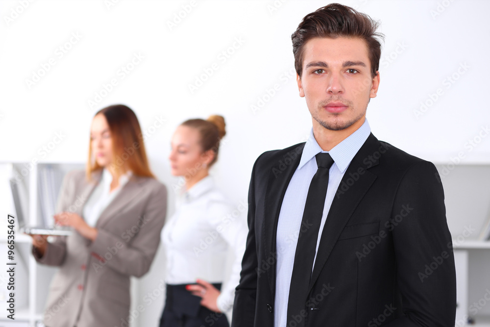 Cheerful business man in office with colleagues in the background, sturt up team Cheerful business man in office with colleagues in the background, sturt up team