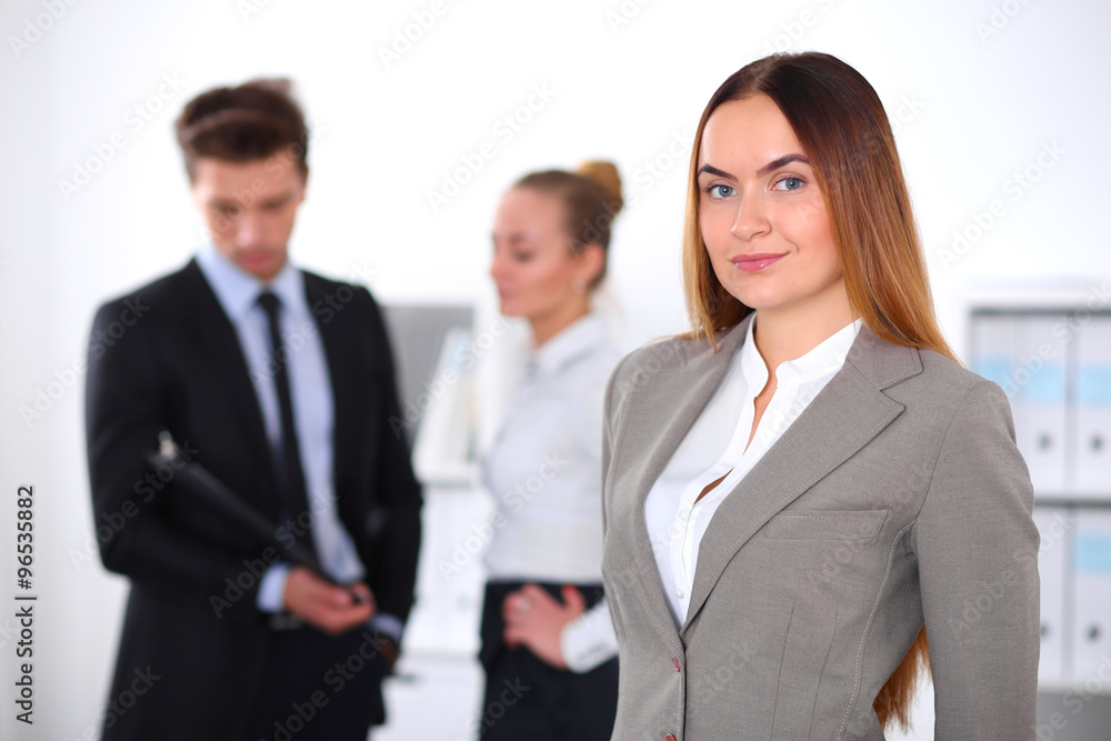 Pretty businesswoman in office with colleagues in the background Pretty businesswoman in office with colleagues in the background