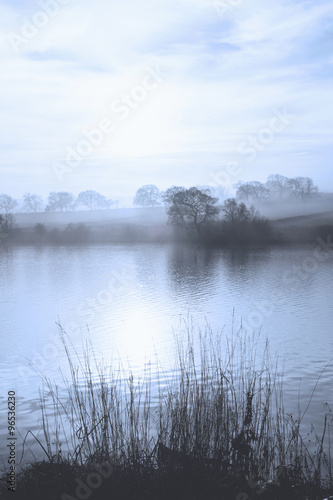 Early morning mist over a calm lake in the North Yorkshire Dales, England. © andrewbretwallis