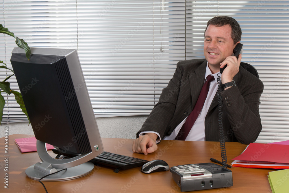Cheerful and charming man in office answering the phone Cheerful and charming man in office answering the phone