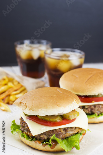 Two burgers, french fries, lemonade on a white wooden background