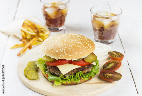 Big burger, french fries, lemonade on a white wooden background